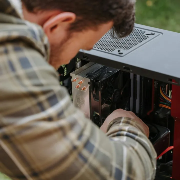 A man cleans and maintains a desktop PC outdoors