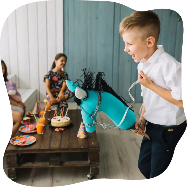 Boy riding hobby horse on birthday party
