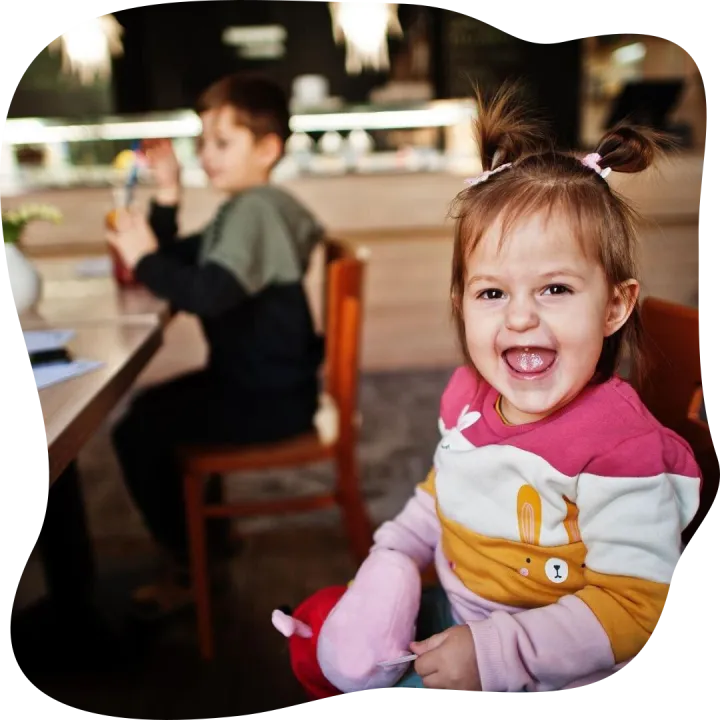 Funny baby girl sitting in cafe and laughs