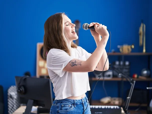 Young woman artist singing song at music studio