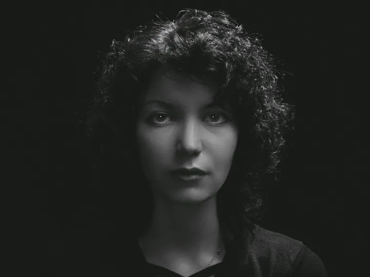 Black and white portrait of a woman with curly hair, highlighting moody and classic tones.
