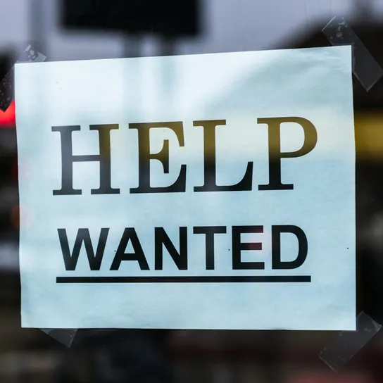 Close-up of a Help Wanted sign taped to a glass