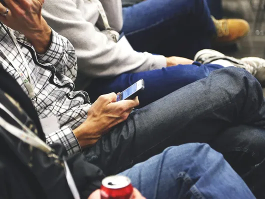 People sitting at a conference casually checking