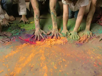 Children's hands mixing brightly coloured craft powder at Messy Church