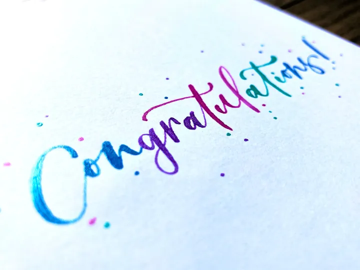 Congratulations in rainbow watercolour brush lettering on white card