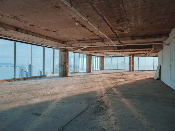 Empty vacant commercial office floor with floor-to-ceiling windows overlooking a city skyline