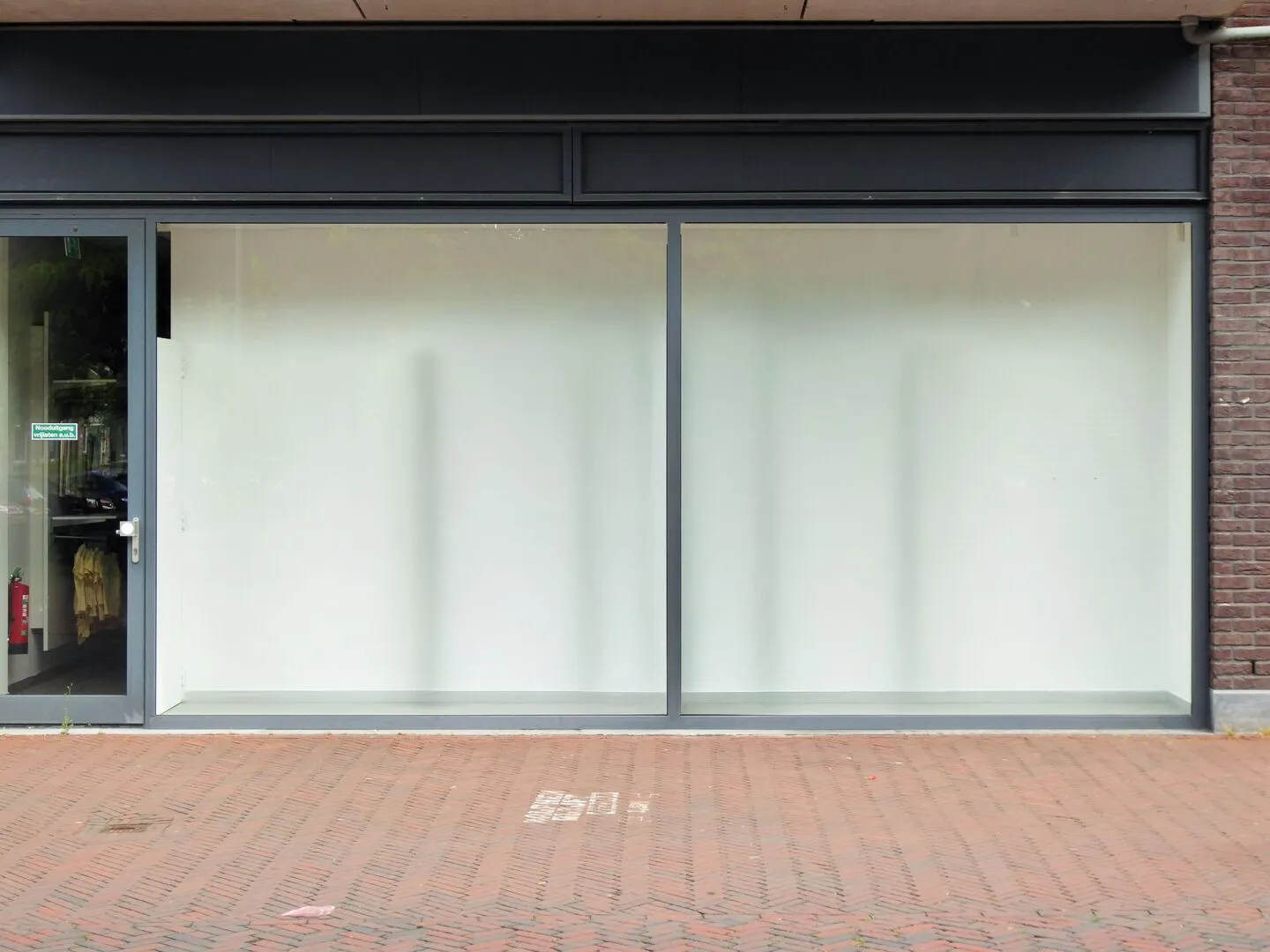 Empty high street retail unit with large glass windows and whitewashed interior