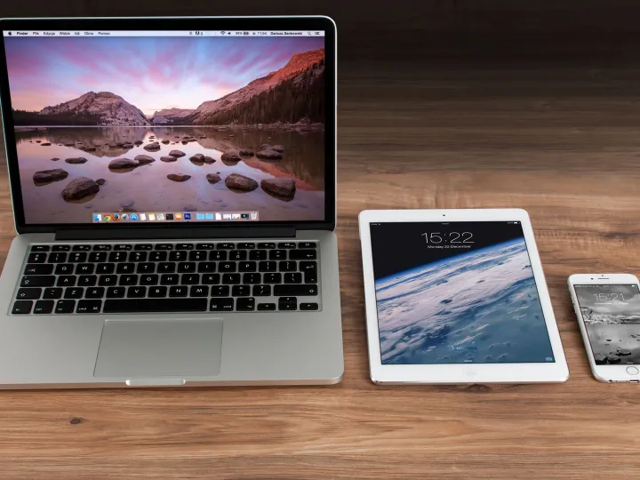 A laptop and a tablet side by side on a wooden desk