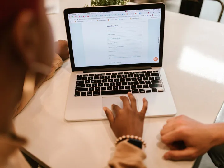 Two people completing an online form on a laptop