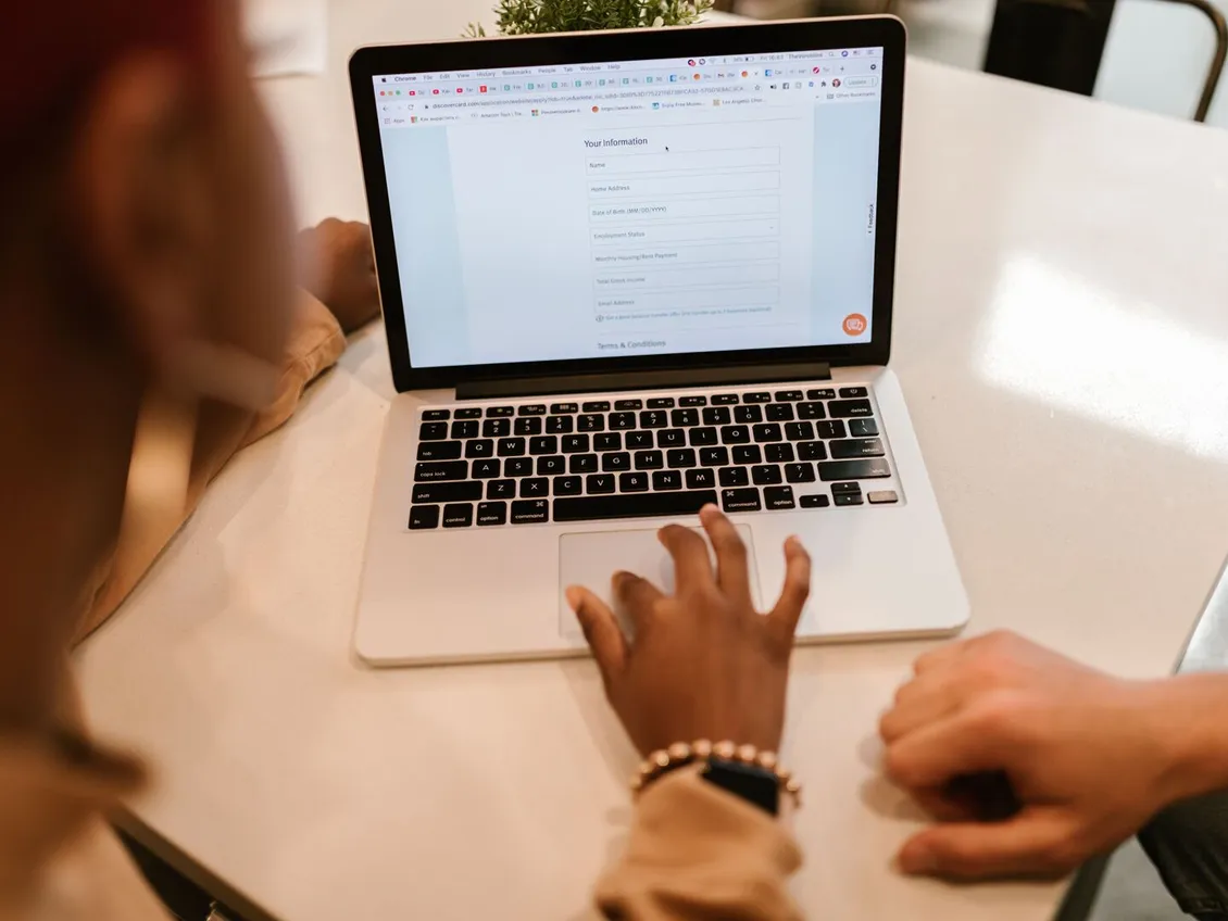 Two people completing an online form on a laptop