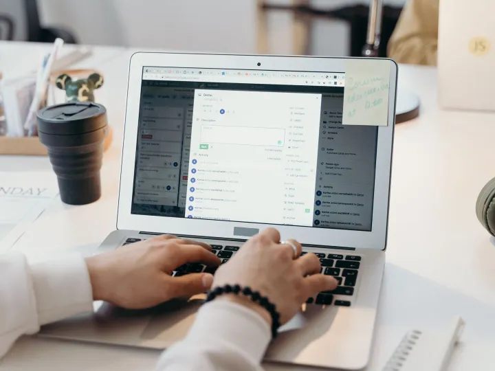 Hands typing an email at a laptop on a bright desk