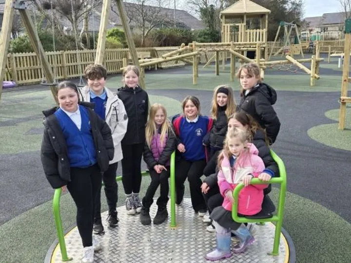 A group of children sitting on a roundabout in a playground