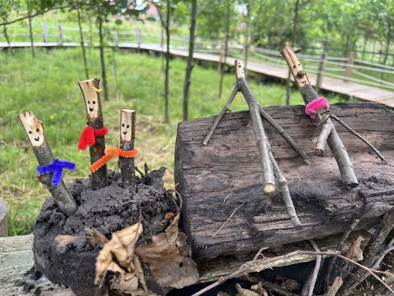 Small figures made from twigs with drawn faces and coloured scarves