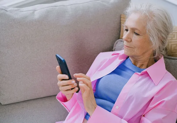Older woman reading church news on her smartphone at home
