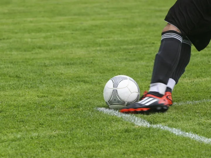 Soccer Player Kicking White Gray Soccer Ball on Green Grass Field