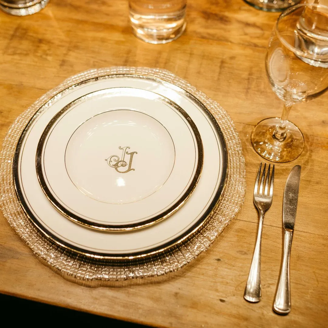 A monogrammed place setting on a wooden dining table