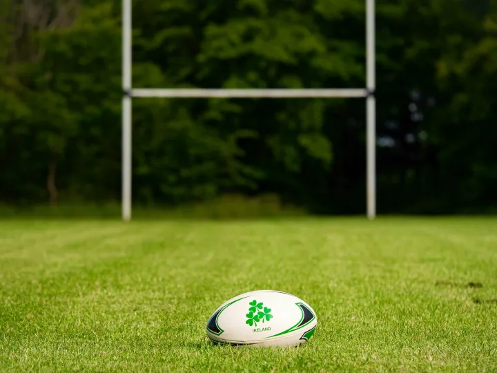 Rugby ball on a grassy field with goal posts in the background, Galway, Ireland.