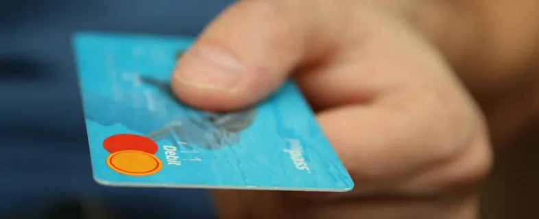 A close-up shot of a hand offering a blue debit