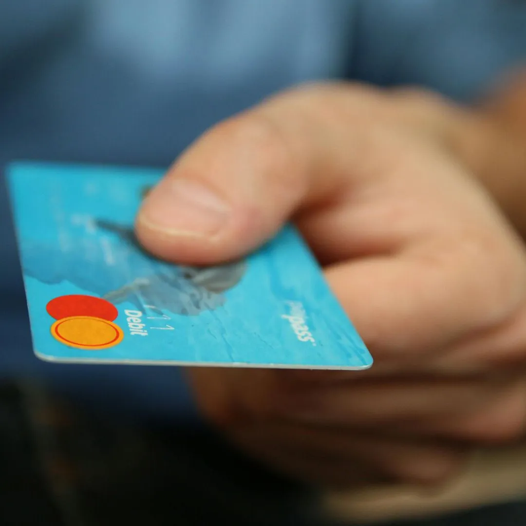 A close-up shot of a hand offering a blue debit
