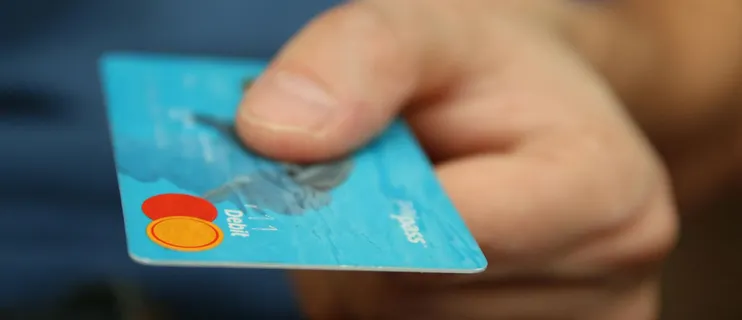 A close-up shot of a hand offering a blue debit