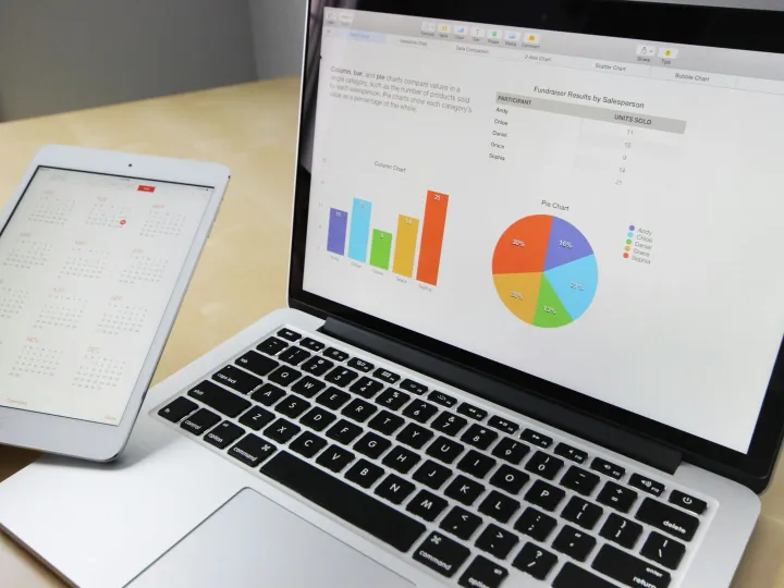 Laptop displaying charts and graphs with tablet ca