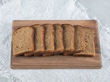 A wooden cutting board with slices of brown bread