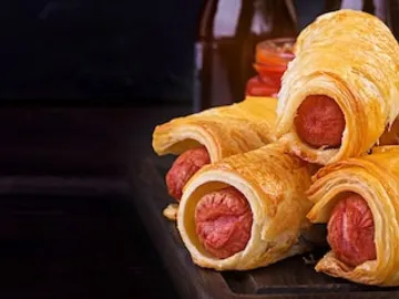 Sausage in the dough on a wooden board with