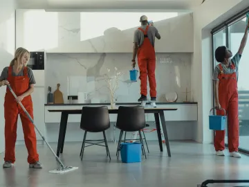 Group of cleaners in red uniforms mopping and wipi