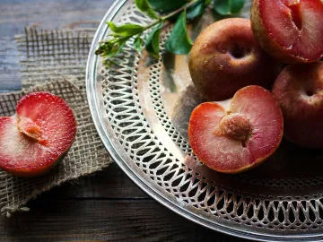 Juicy ripe red plums on a decorative silver plate, capturing freshness and health benefits.