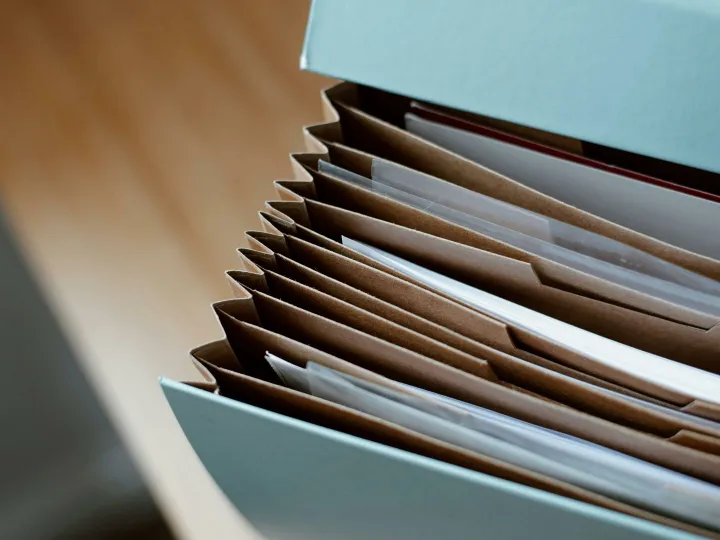 High angle of opened briefcase for documents with papers accosted in order placed on wooden table