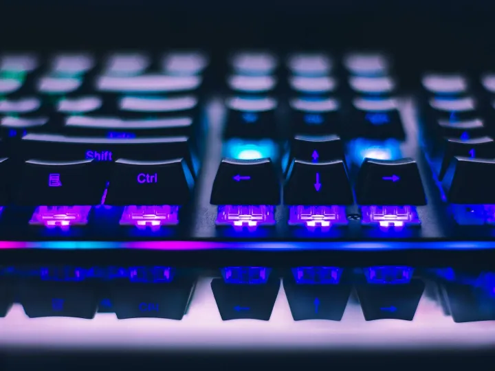 A detailed close-up of illuminated mechanical keyboard keys with focus on blue and purple lights.