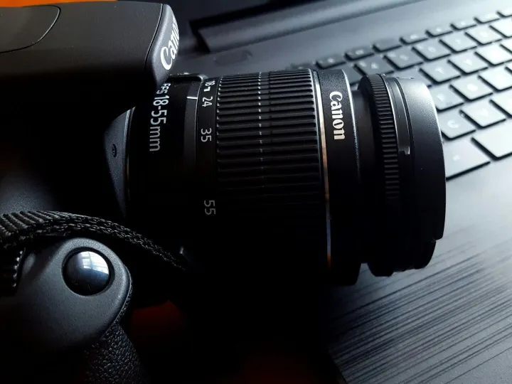 Close-up of a black DSLR camera with lens on a lap