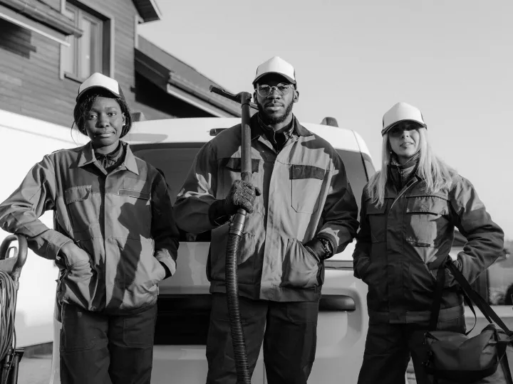 Three professional cleaners in uniform pose with e