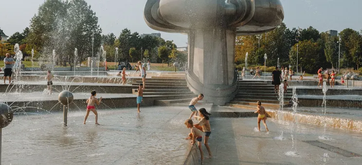 Children playing in an outdoor water fountain on a sunny day